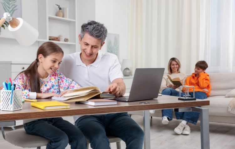 dad and daugher at table studying. Mom and son reading on couch