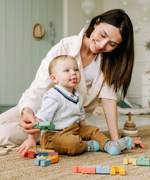 mom sitting on floor playing with baby